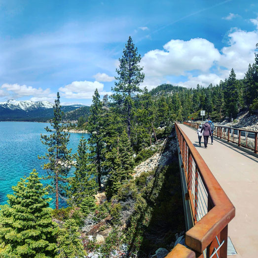 Scenic lake view with forested walking trail.